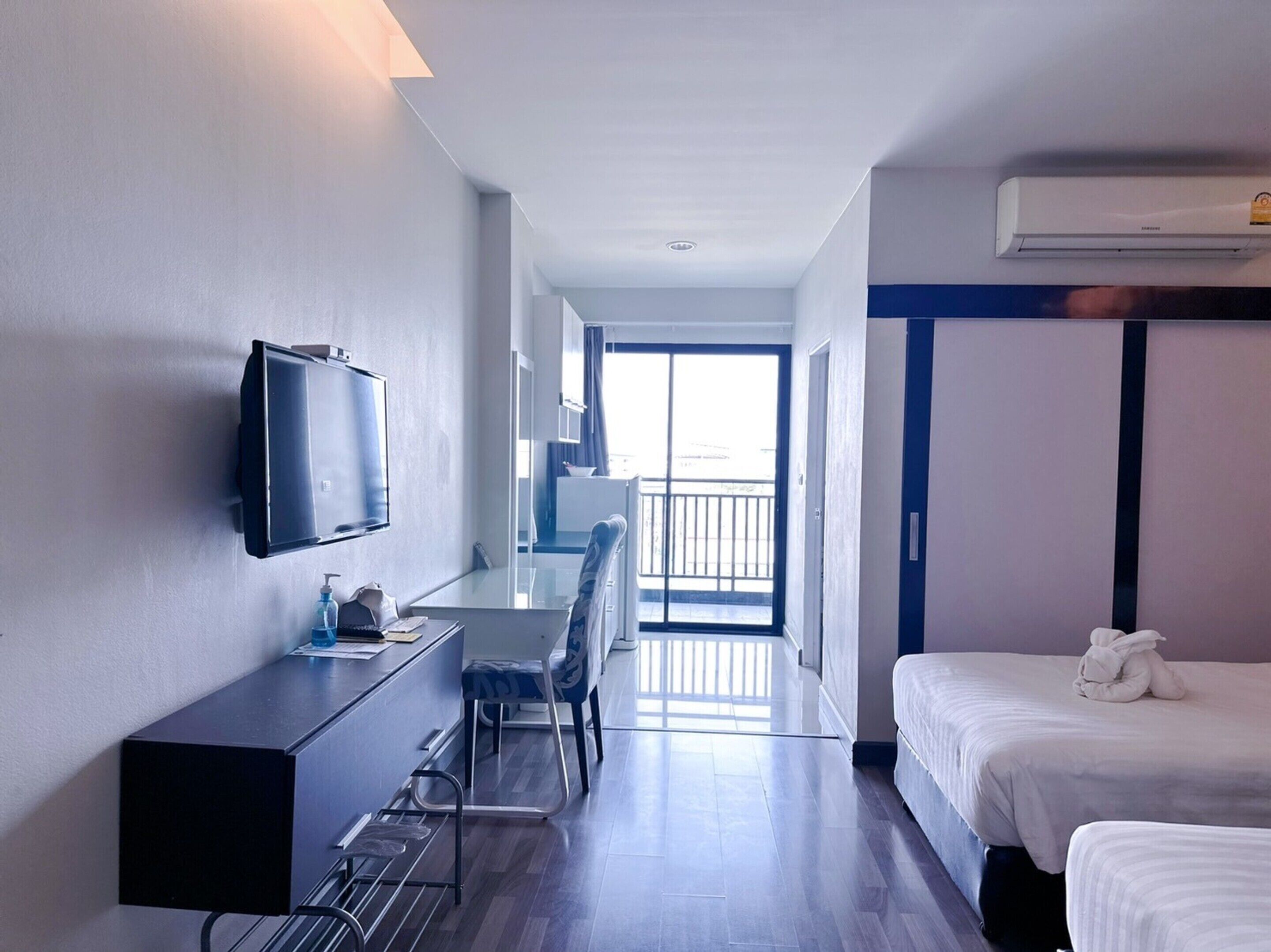 Une chambre d’hôtel avec un lit, un bureau et une chaise, une télévision et un balcon avec vue.