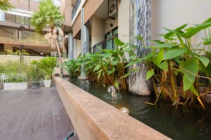 A modern building with a water feature, including a fountain and a small pond with plants.