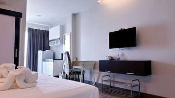 Een hotelkamer met een bed, een bureau, een stoel, een aan de muur bevestigde televisie en een klein plankje met toiletartikelen.