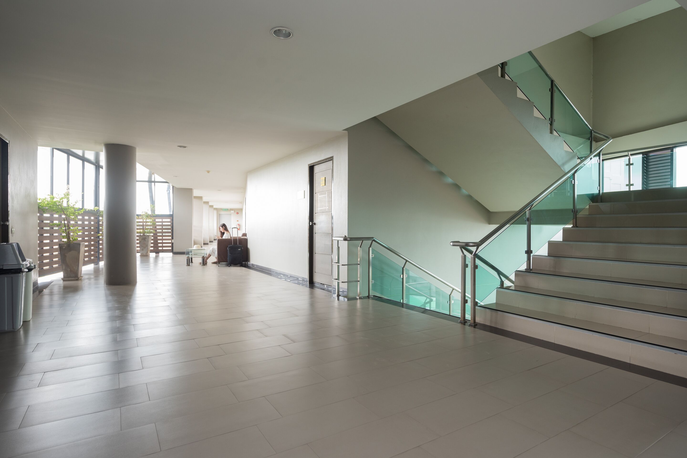 A spacious lobby with a staircase, large windows, and a clean, modern design.