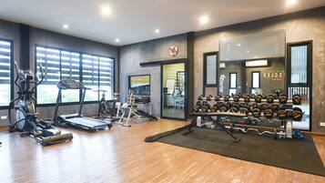 A gym with treadmills, elliptical machines, and a rack of dumbbells.
