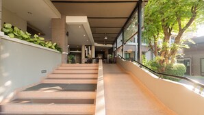 A modern staircase with a glass railing, leading to an indoor area with seating and plants. - Romyen Garden Place (Nakhon Ratchasima)