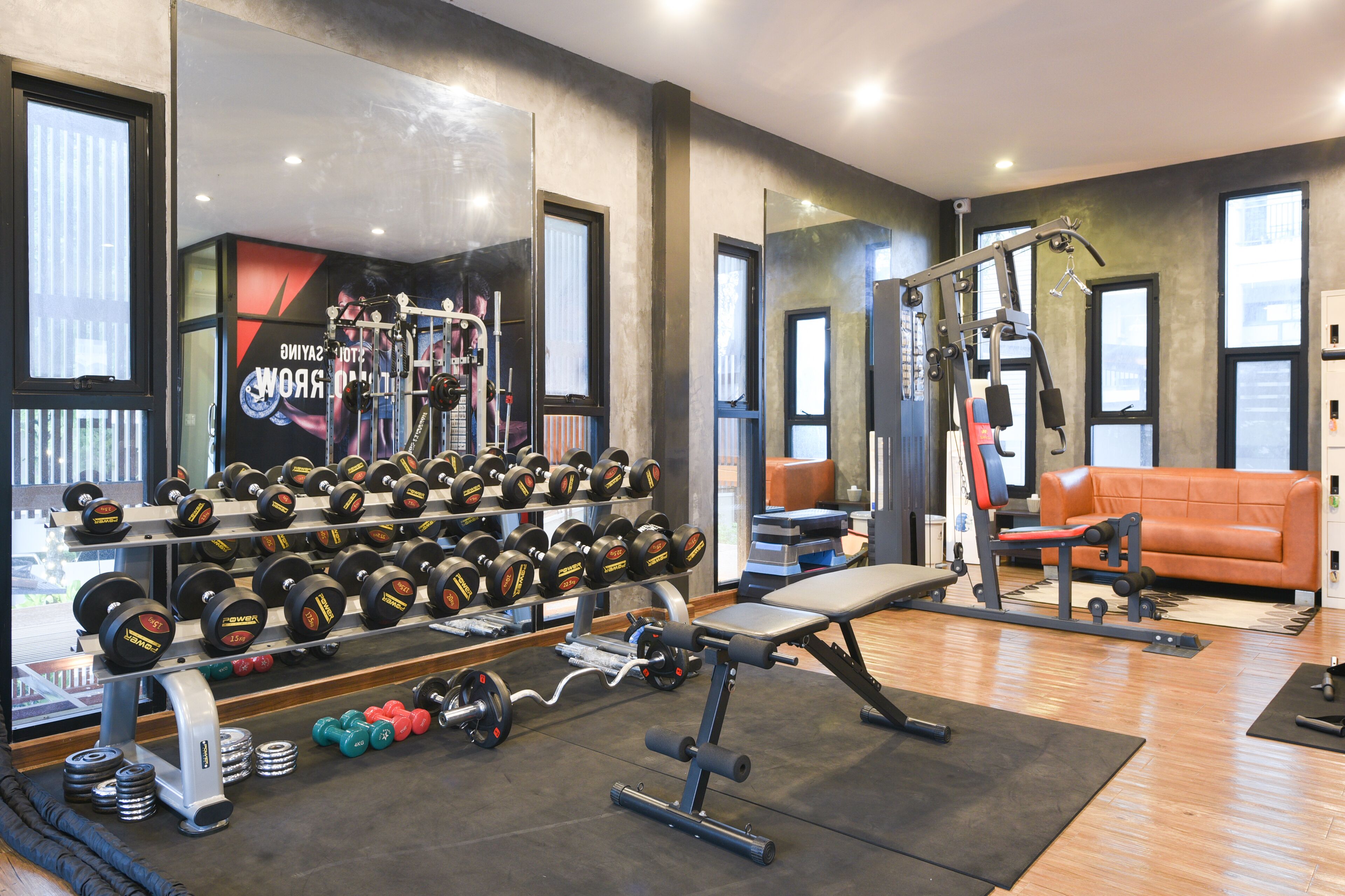 Uma academia com equipamentos de musculação, halteres e um banco.