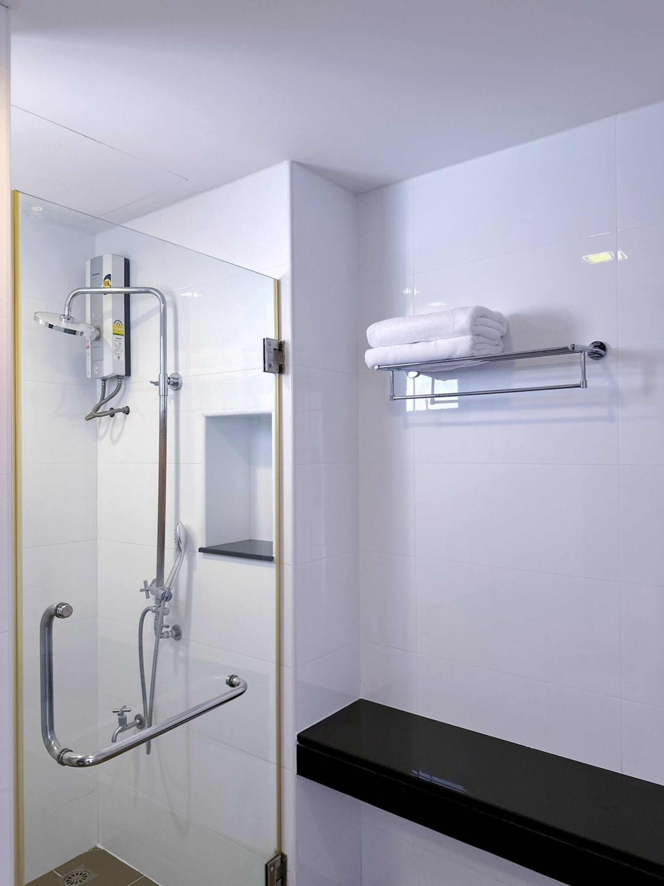 Ein modernes Badezimmer mit Duschkabine aus Glas, einem Handtuchhalter und einer schwarzen Ablage.
