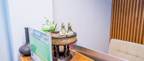 A reception area with a wooden counter, a menu stand, and a decorative tea set.