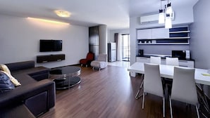 A modern hotel room with a living area, a dining table, and a kitchenette. - Romyen Garden Place (Nakhon Ratchasima)