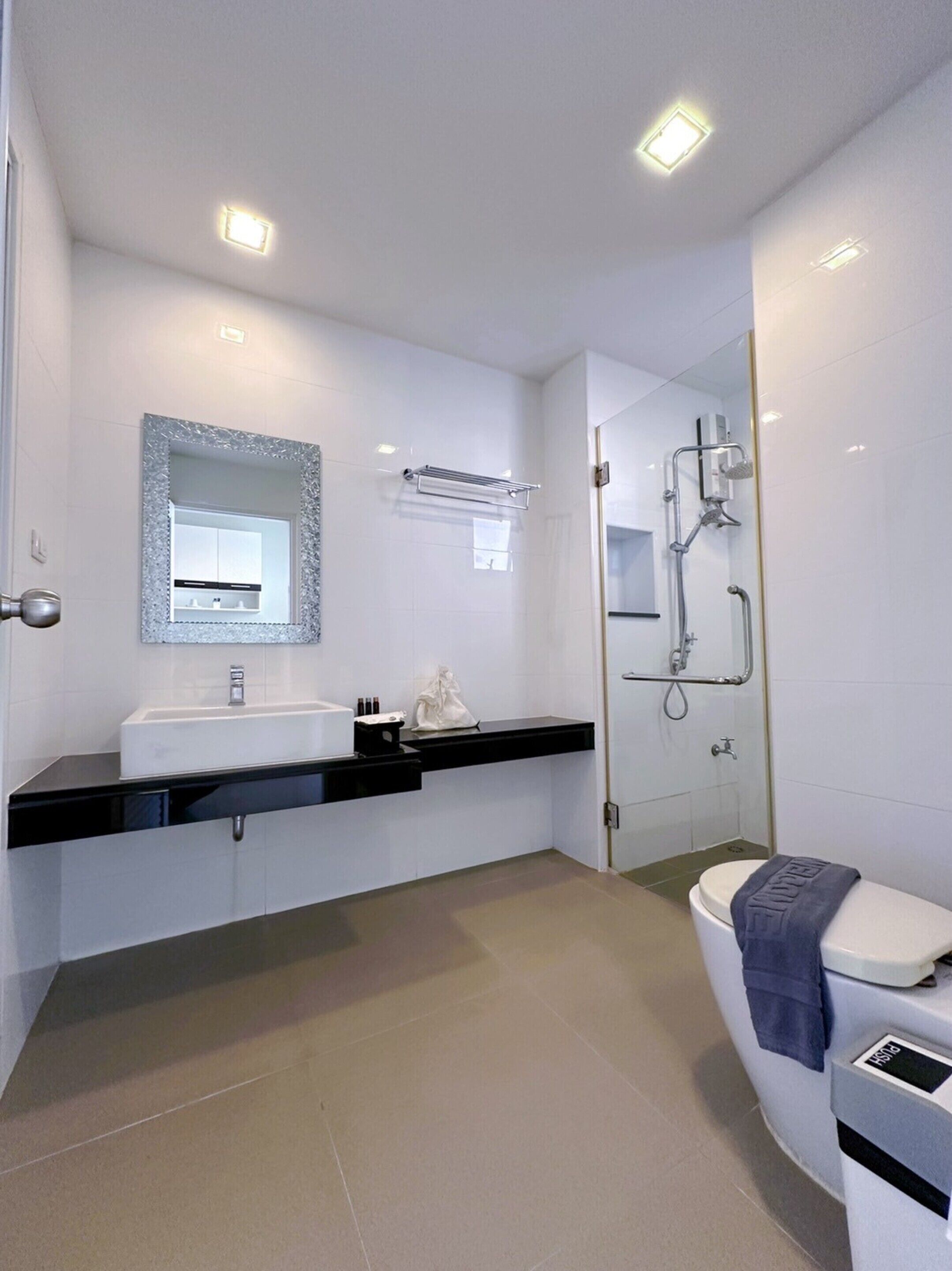 A modern bathroom with a white sink, mirror, and toilet.