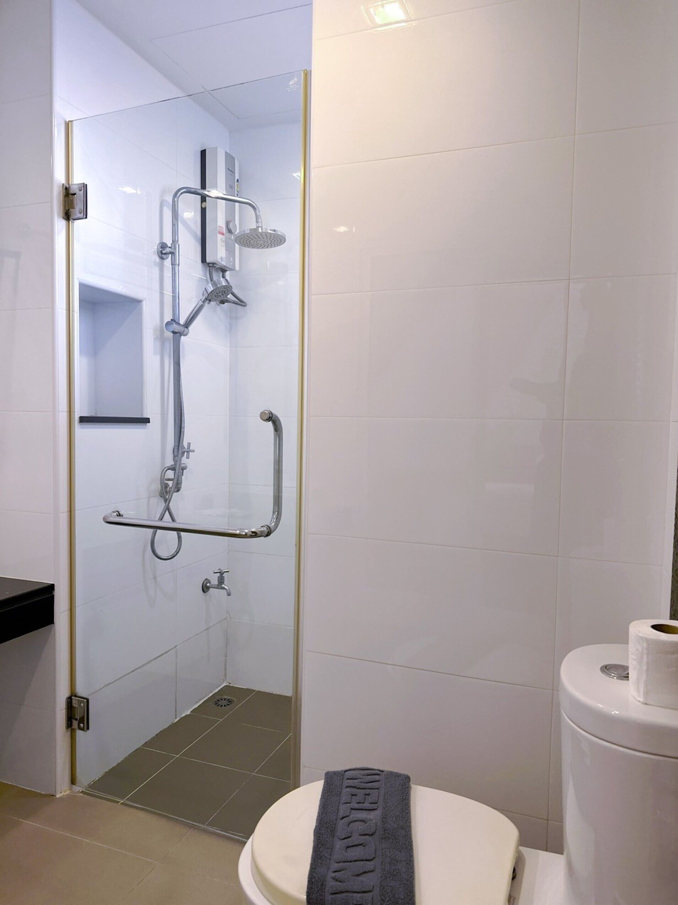 Une salle de bain équipée d’une douche, de barres d’appui, de toilettes et d’un porte-serviettes.