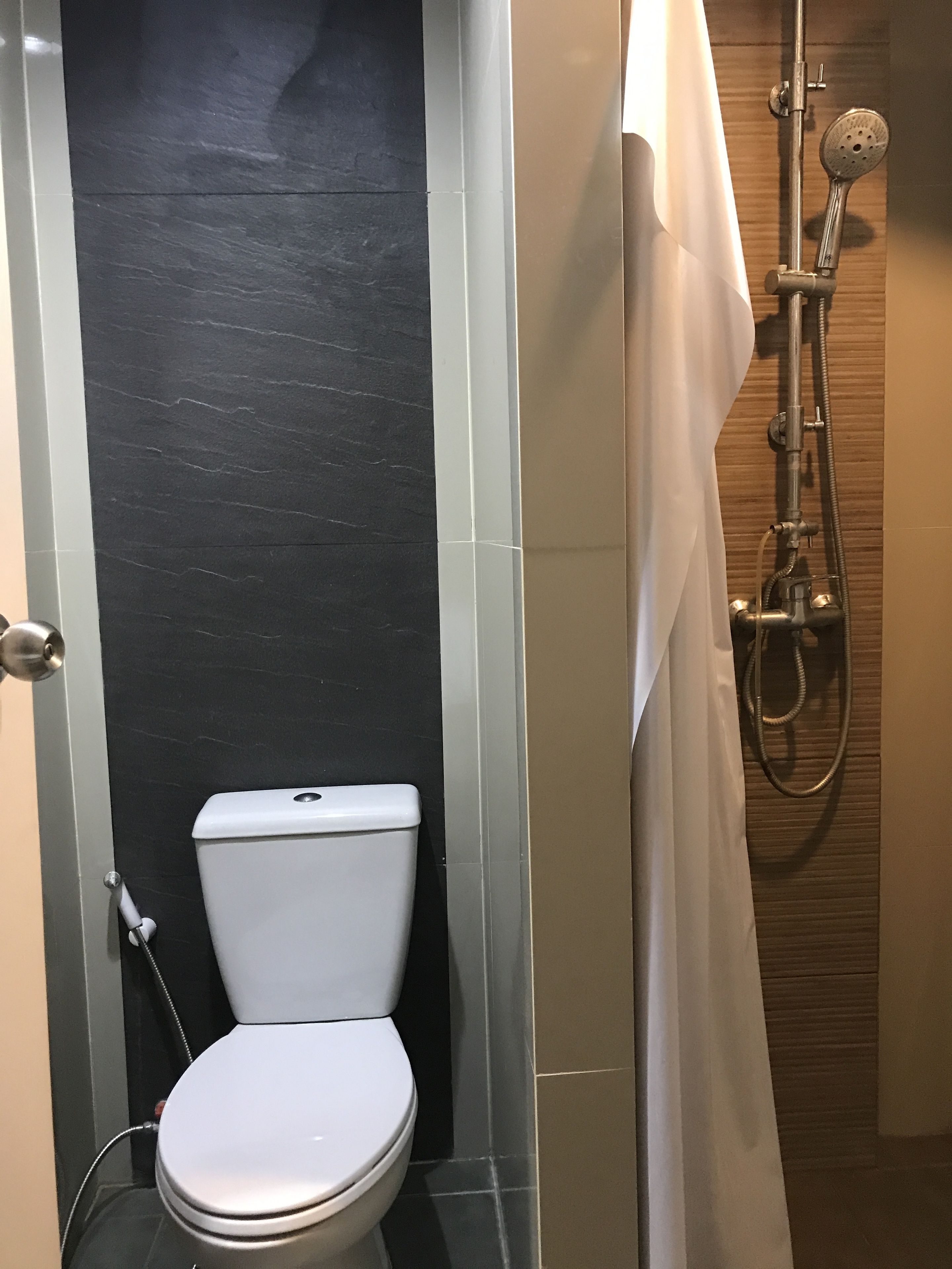 A bathroom with a toilet, a shower, and a towel rack.