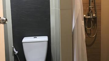 A bathroom with a toilet, a shower, and a towel rack.