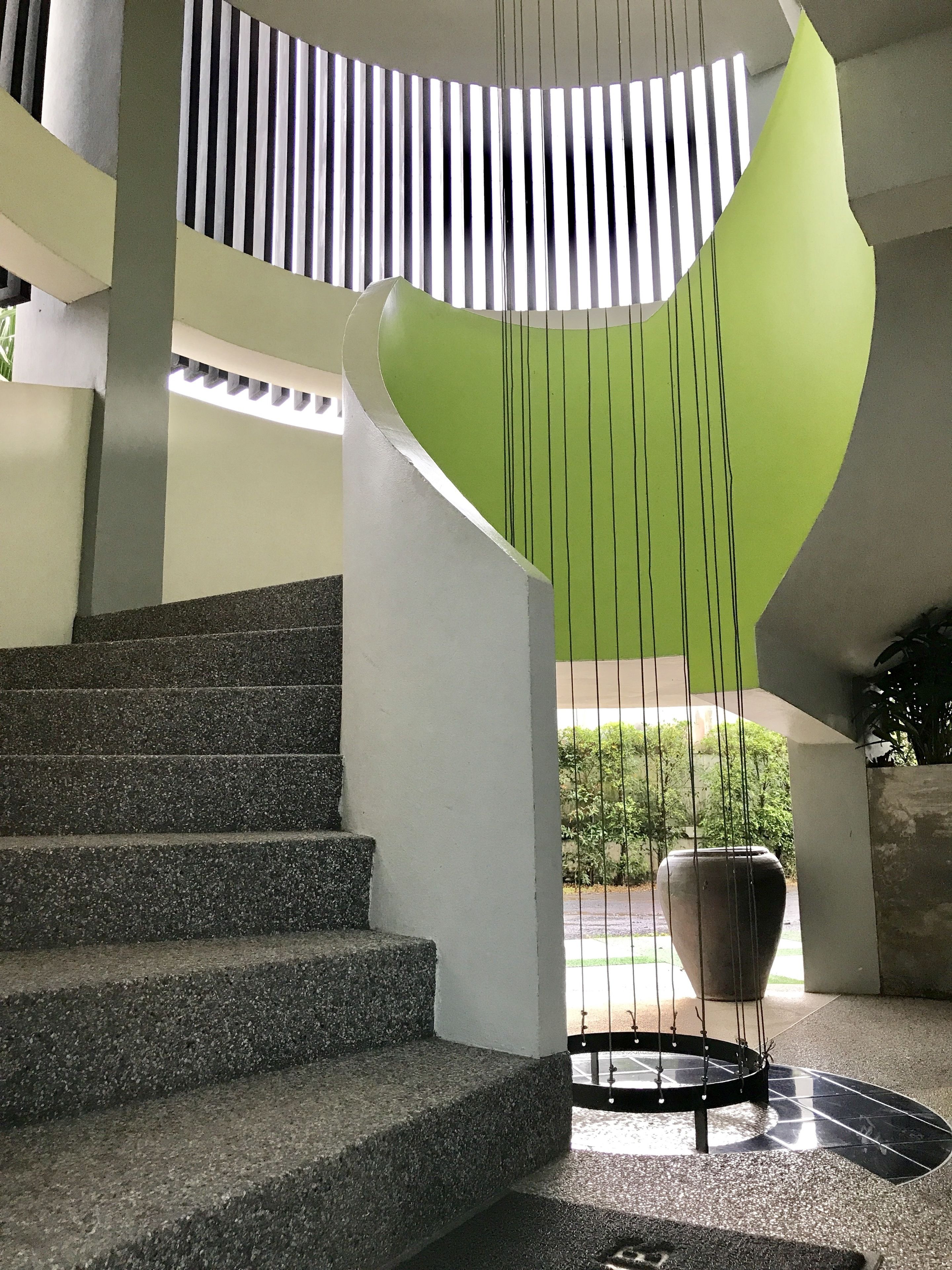Un escalier au design moderne, menant à une structure murale verte et incurvée.