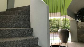 Un escalier au design moderne, menant à une structure murale verte et incurvée.