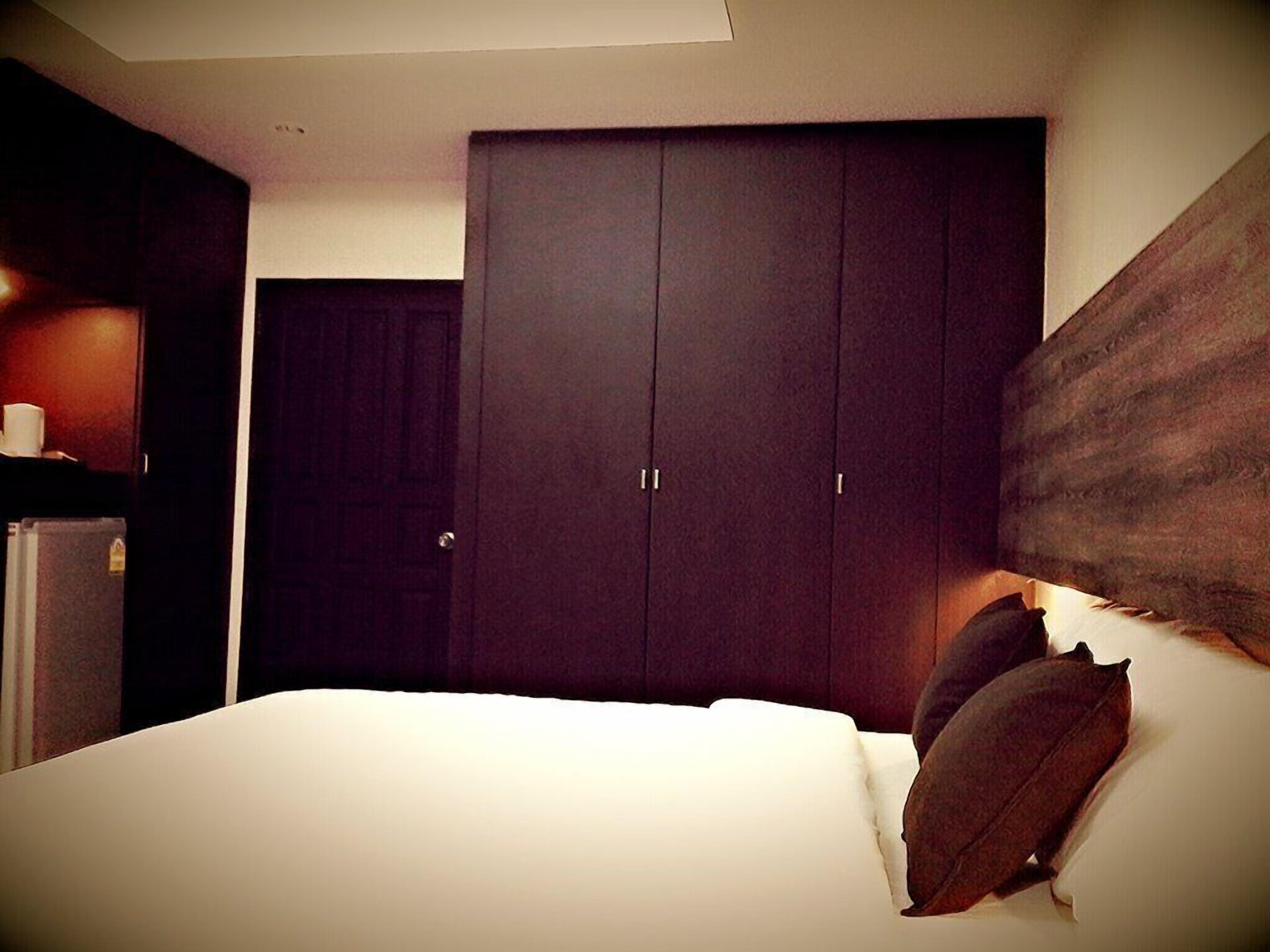 Un dormitorio con una cama grande, un armario de madera oscura y una mesita con una taza.