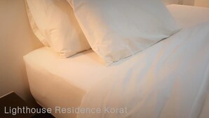 Una cama bien hecha con sábanas y almohadas blancas, que sugiere una habitación limpia y bien cuidada.