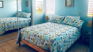 Un dormitorio con dos camas, un espejo grande y una ventana con persianas.