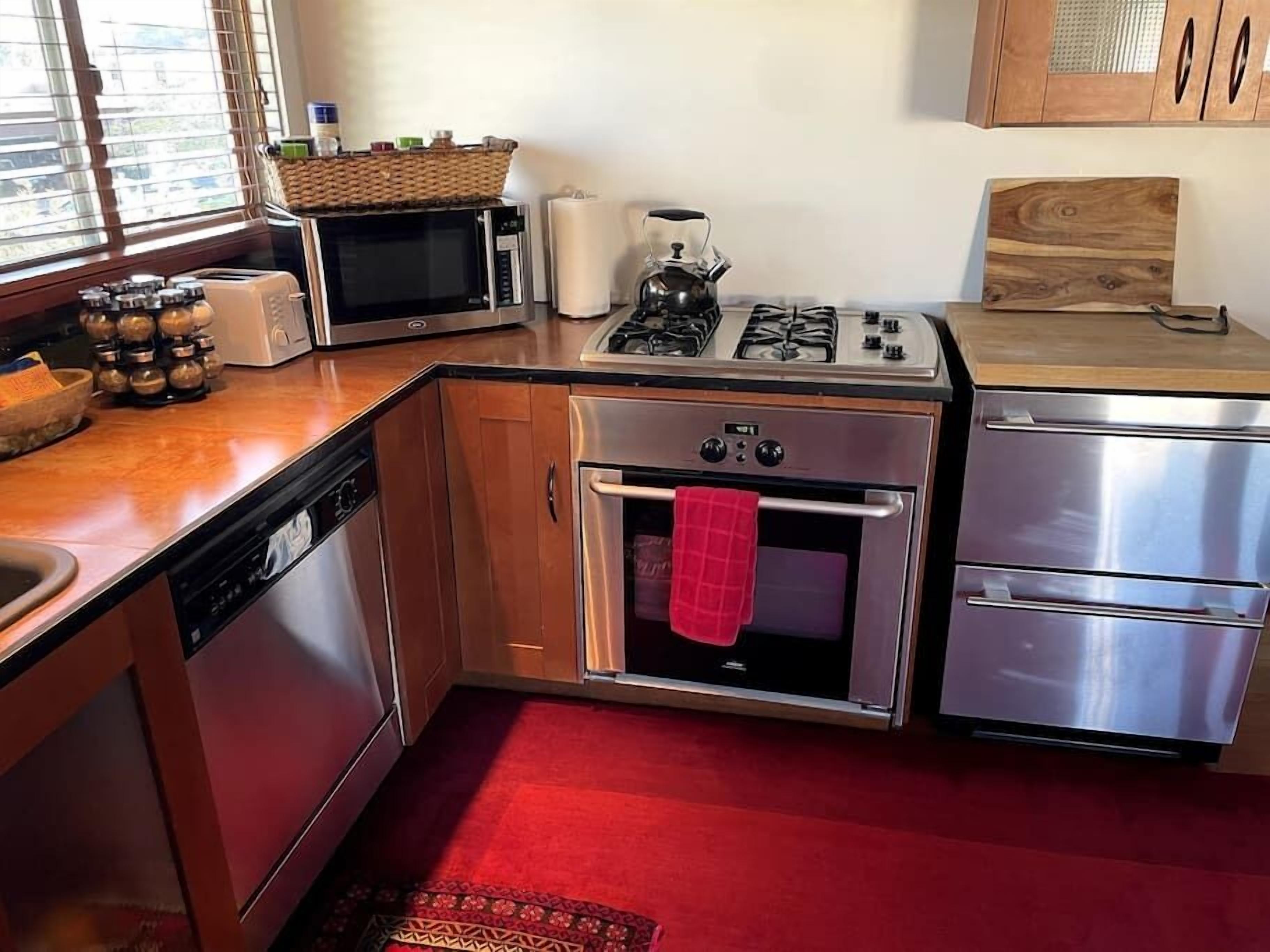 Una cocina compacta con microondas, estufa, horno y lavavajillas.