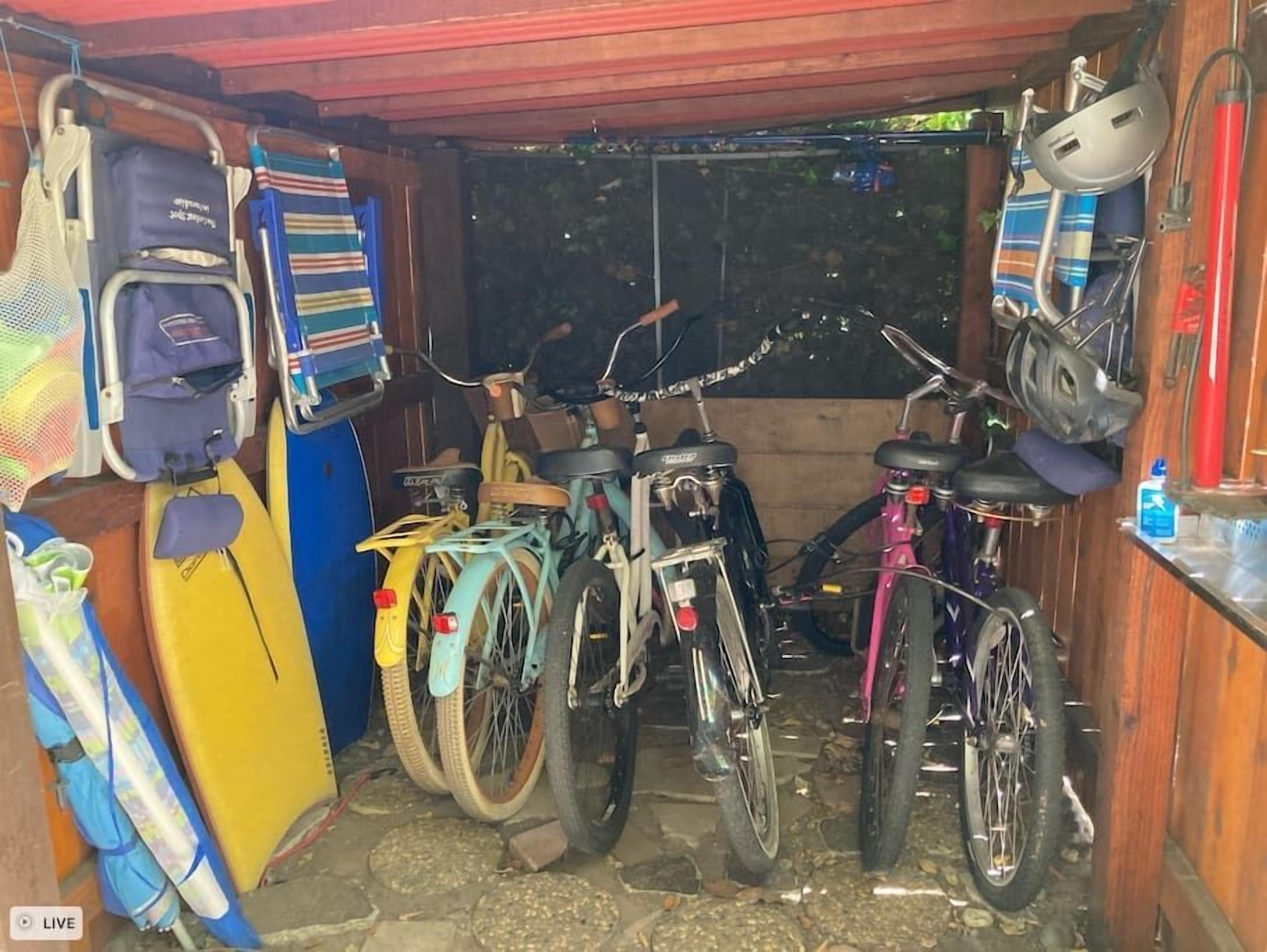 Un espace de stockage pour vélos contenant plusieurs vélos, une planche de surf et un casque.