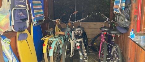 Un espace de stockage pour vélos contenant plusieurs vélos, une planche de surf et un casque.