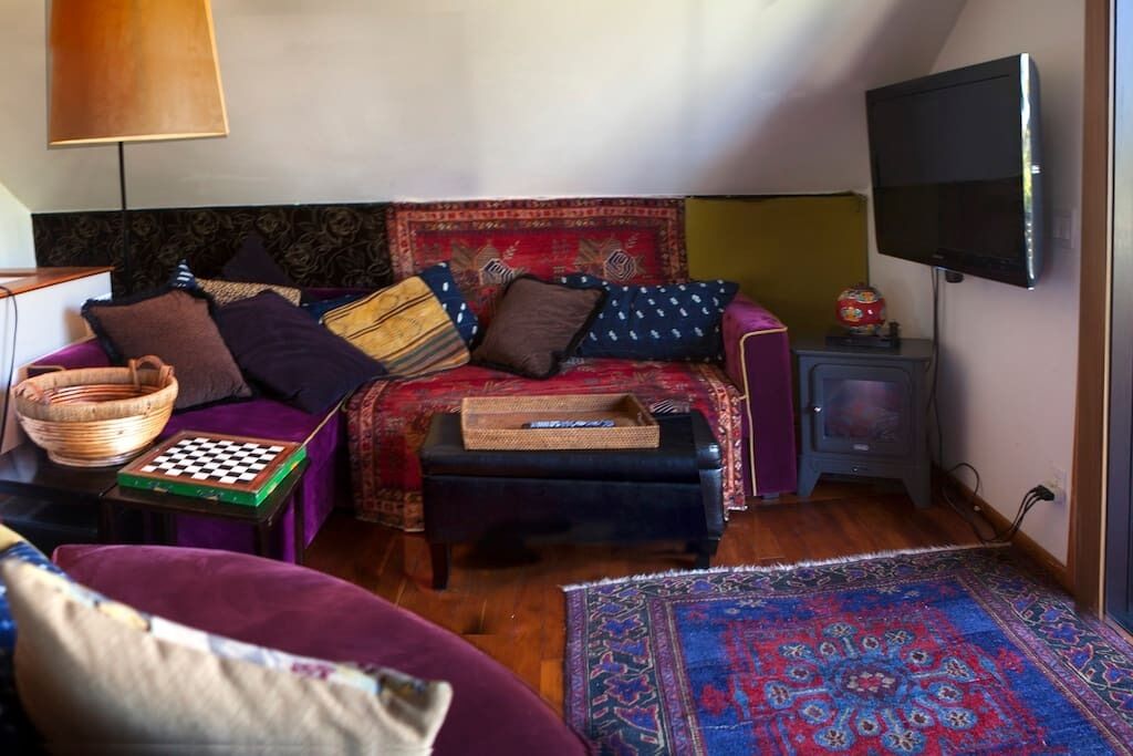Una sala de estar acogedora con un sofá, una pequeña mesa con un tablero de ajedrez, un televisor y una alfombra estampada.