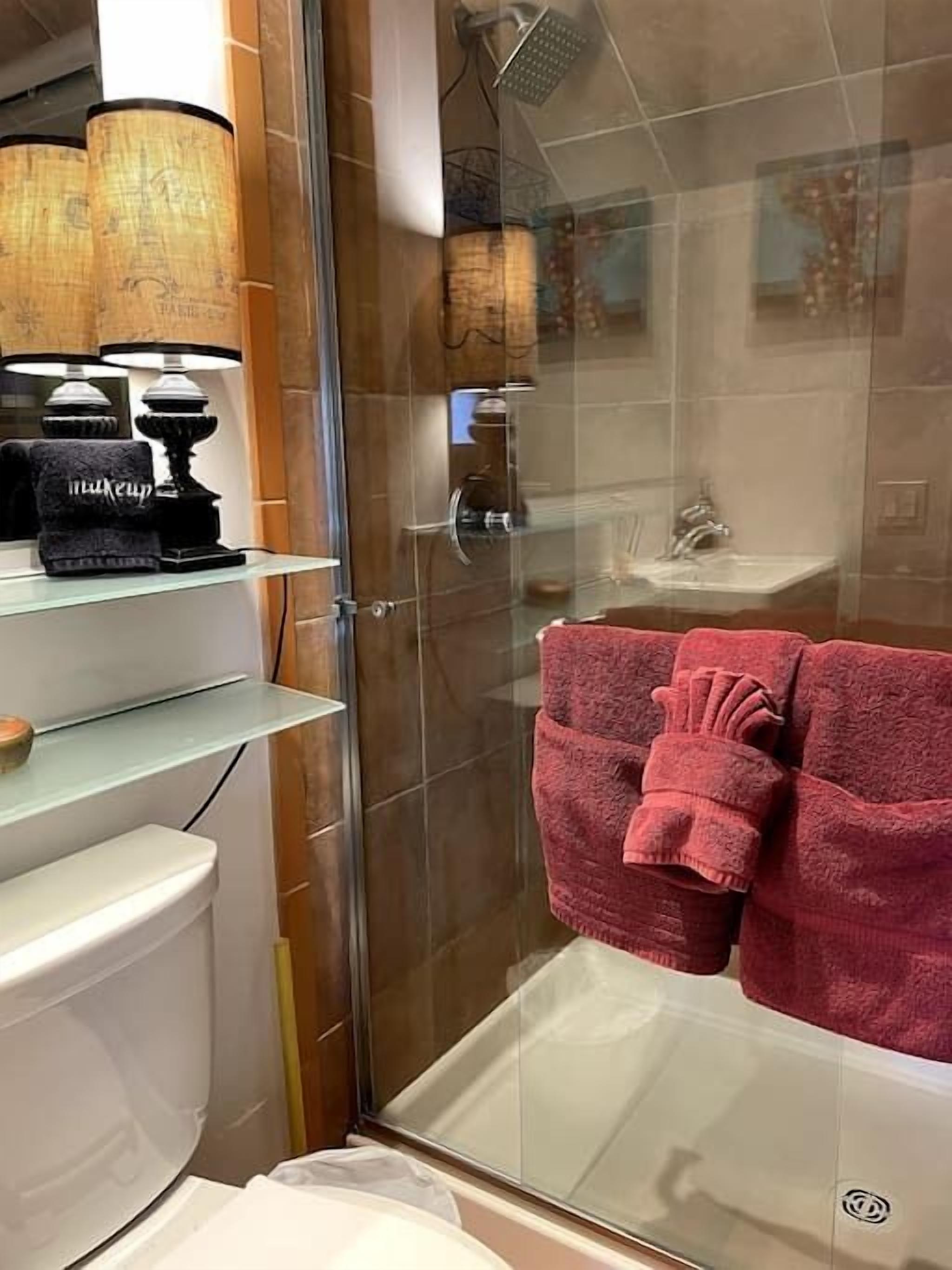 A modern bathroom with a glass shower enclosure, a white toilet, and a glass sink.