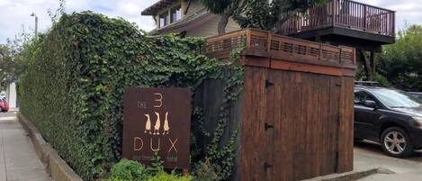 A sign for "The 3 DUX apartment hotel" with a wooden gate and a balcony.