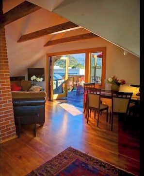 Relax in a spacious room with a high ceiling, sofa, armchairs, and a dining table, offering a view of the outdoors.