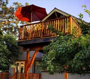 Guests can enjoy a balcony with a wooden railing, surrounded by lush greenery.