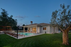 Una casa moderna con piscina, un porche cubierto y un césped bien cuidado.