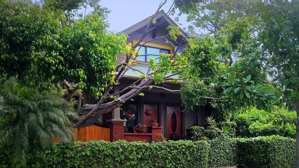A traditional house with a tiled roof, surrounded by lush greenery and a well-maintained garden.
