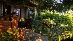 A brick house with a front porch, a small garden, and a pathway leading to the door.