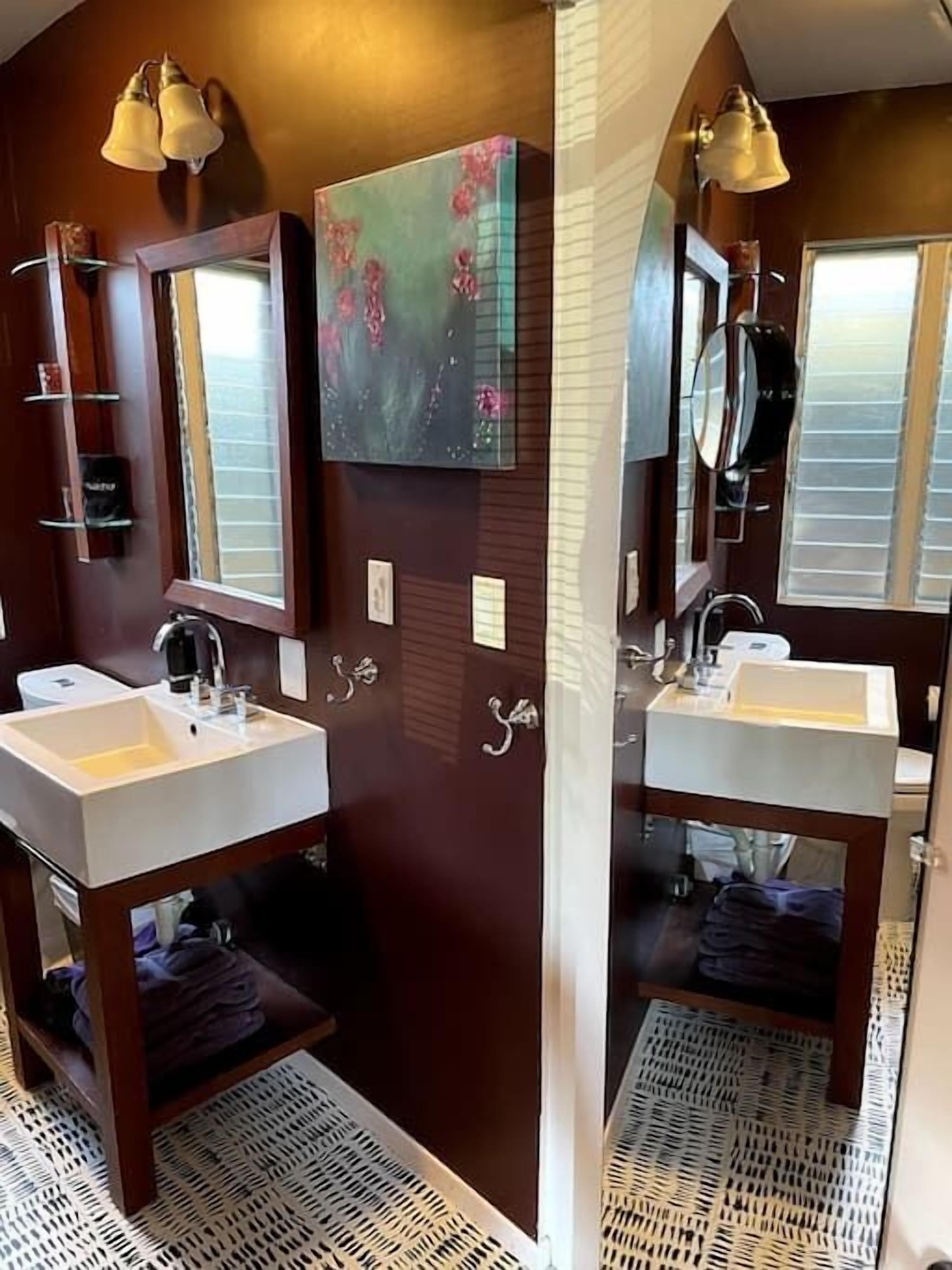 Un baño moderno con dos lavamanos, un espejo grande y un cuadro en la pared.