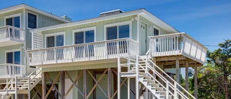 A multi-story house with a covered porch and a staircase leading to the upper levels.