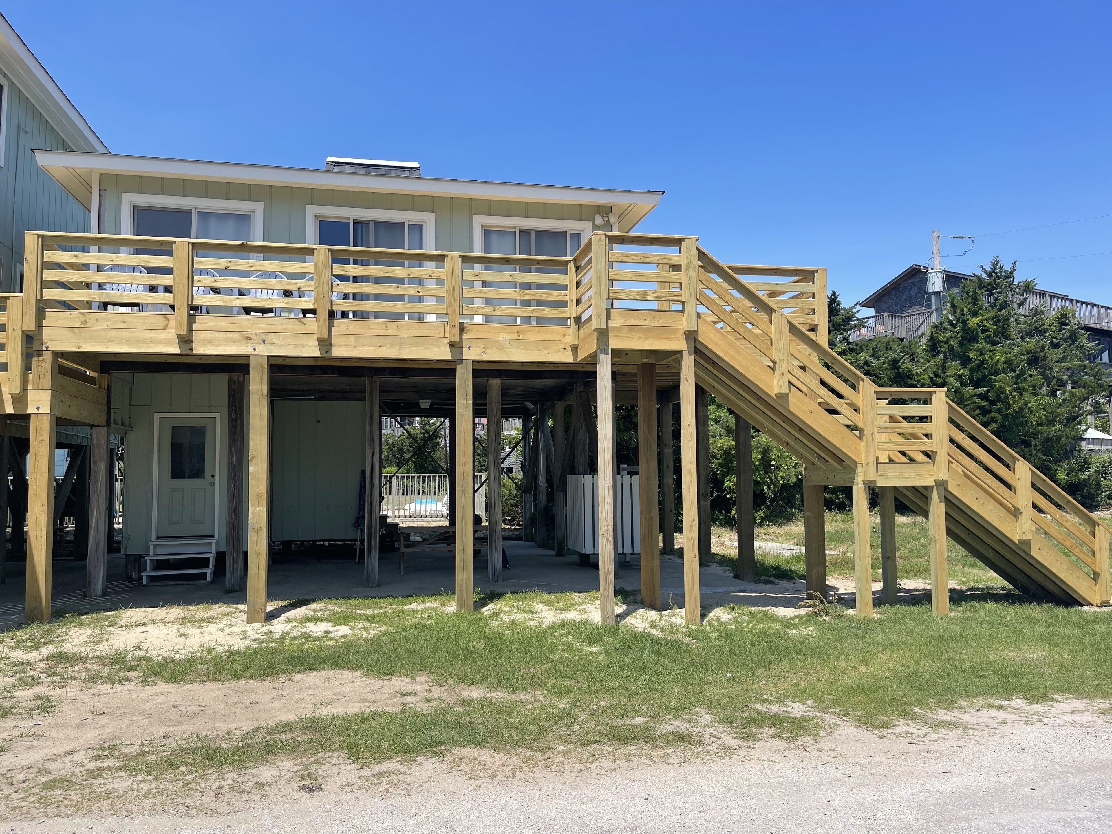 A two-story house with a wooden deck and a staircase leading to the upper floor.