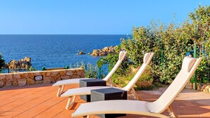 Una terraza con sillones de descanso y un muro de piedra con vistas al mar.