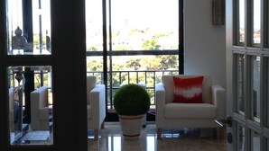 A room with a white sofa, a red pillow, and a potted plant.