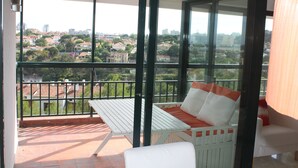 A balcony with a white table and bench, offering a view of a cityscape.