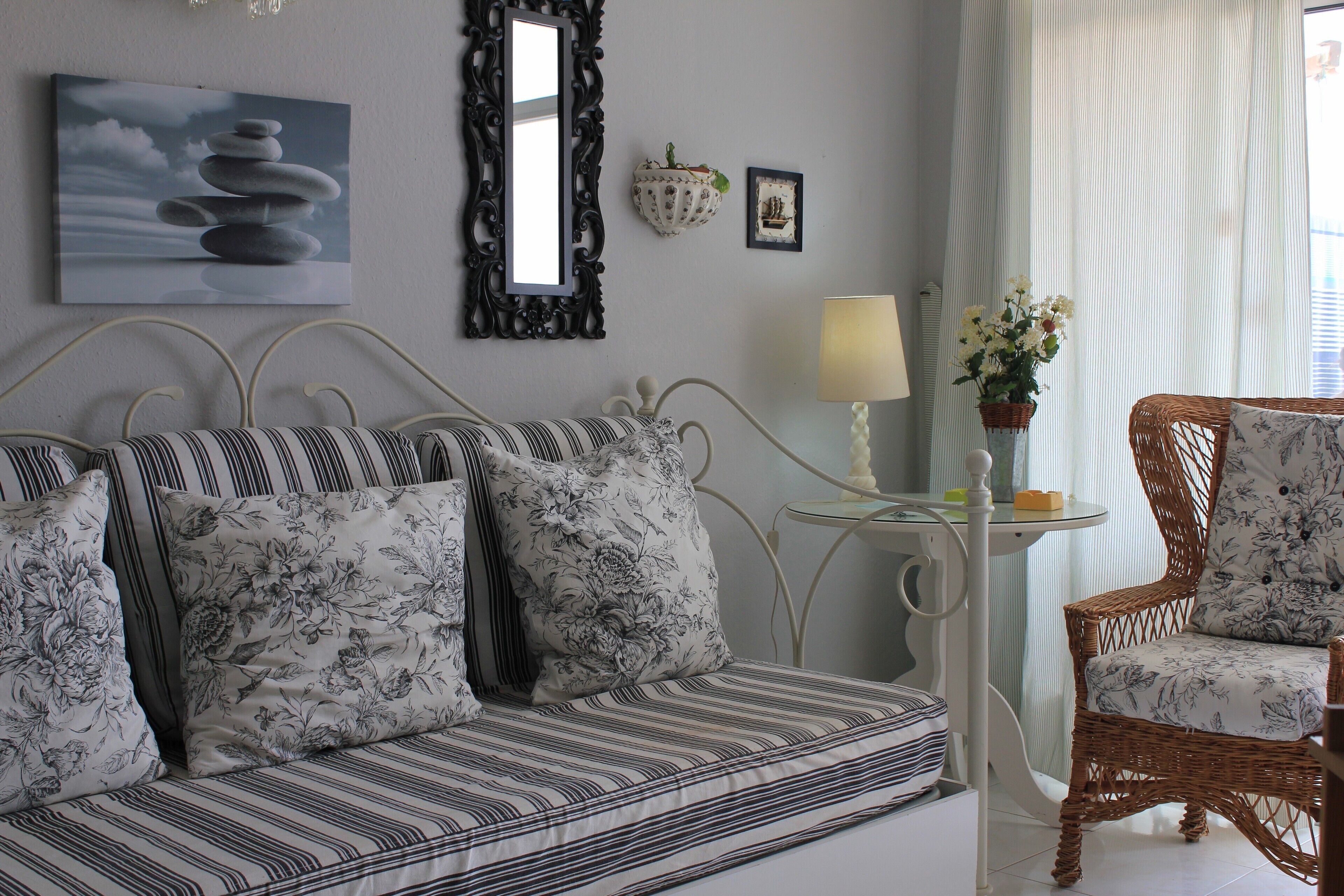 Quarto com cama, uma cadeira, mesa com abajur e parede com pintura e espelho.