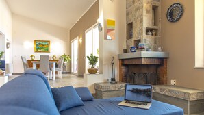 Un salon moderne avec un canapé bleu, une cheminée et un ordinateur portable posé sur le canapé.