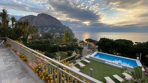 Un espace piscine offrant une vue sur la mer et sur une montagne en arrière-plan.