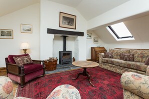 A living room with a fireplace, a sofa, a chair, and a round table.
