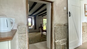 A room with a stone wall, a white door, a white kettle on a wooden counter, and a window with a view of the outdoors. - Delightful 300 year old cottage in quiet country lane (Crowlas)