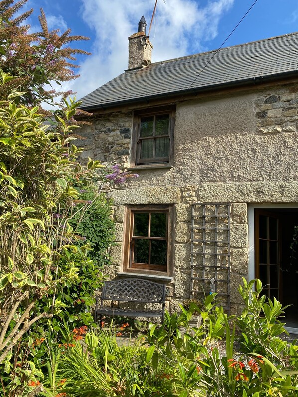 A stone house with a chimney, a window, and a door.