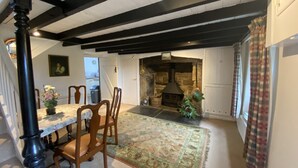 A dining area with a table, chairs, and a rug. There is a fireplace in the background. - Delightful 300 year old cottage in quiet country lane (Crowlas)