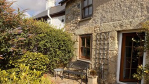 A stone house with a garden patio, a bench, and a statue. - Delightful 300 year old cottage in quiet country lane (Crowlas)