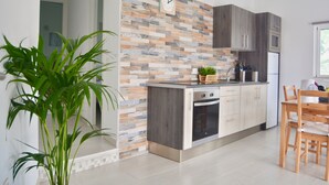 Una cucina moderna con rivestimento piastrellato, mobili in legno, forno integrato e zona pranzo con tavolo e sedie in legno.