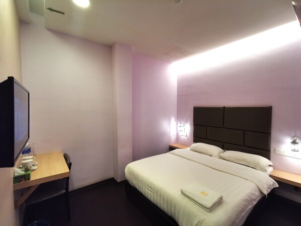 A hotel room with a bed, a desk, a TV, and a nightstand.