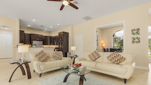 A spacious living room with a beige sofa set, a glass coffee table, and a ceiling fan. - Dream villa with tropical garden on the canal (Cape Coral)