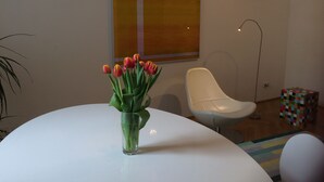 A modern room with a white table, a glass vase with tulips, a white chair, and a colorful cube structure.