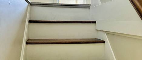 Una escalera con paredes blancas y peldaños de madera.