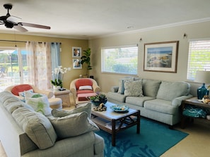 A living room with a sofa, armchair, coffee table, and a ceiling fan.